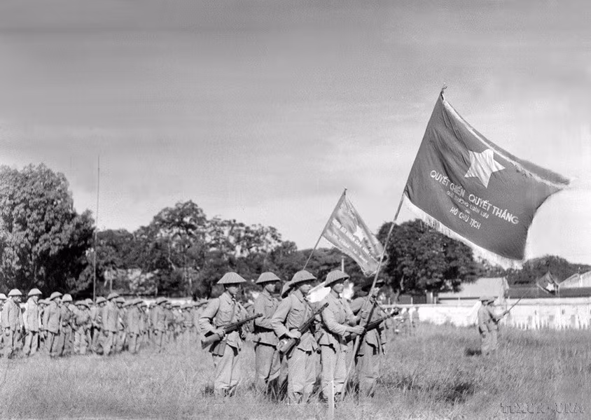 Una unidad de la División de la Capital, enarbolando la bandera “Determinación para luchar, determinación para vencer” entregada por el Presidente Ho Chi Minh realiza la primera ceremonia de izado de bandera después de la liberación de Hanói, en el patio de Cot Co (Torre de la Bandera), actual puerta de Doan Mon de la Ciudadela Imperial de Thang Long.