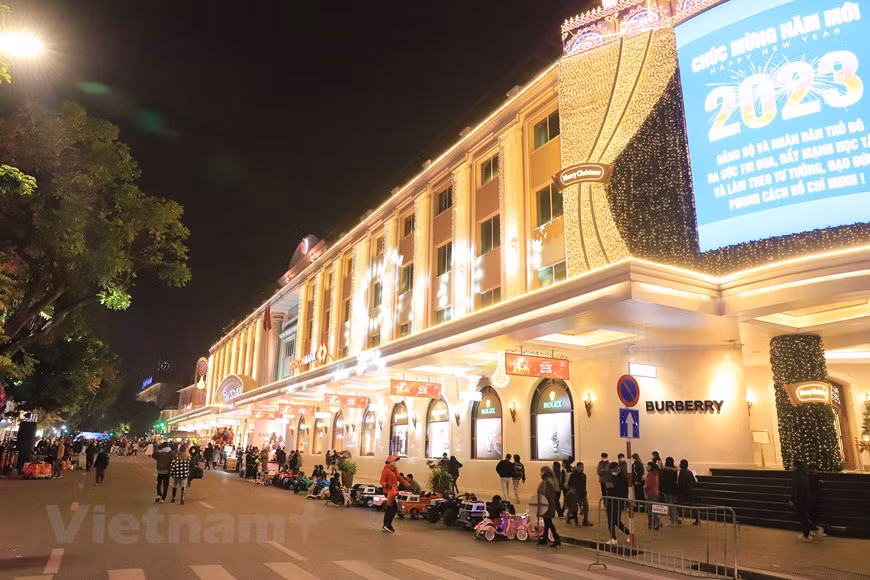 El centro comercial Trang Tien Plaza brilla con luces doradas y los paneles. El centro comercial Trang Tien Plaza brilla con luces doradas y los paneles.