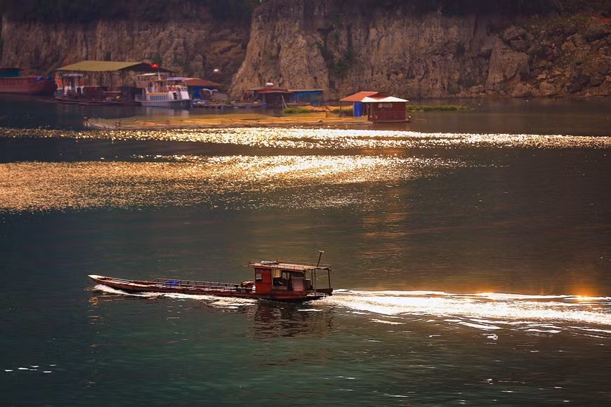 Escena tranquila en la tarde de otoño, con el sol dorado que brilla en la superficie del lago Hoa Binh.