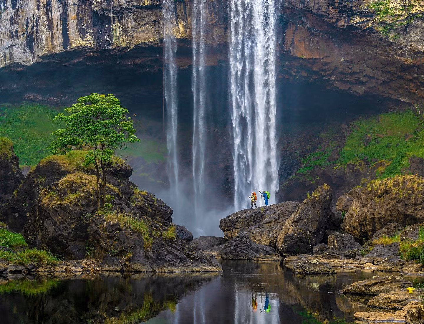 Al pie de la cascada, bloques de piedra con formas interesantes, apilados uno encima del otro, forman grandes escaleras en medio del agua azul plateado.