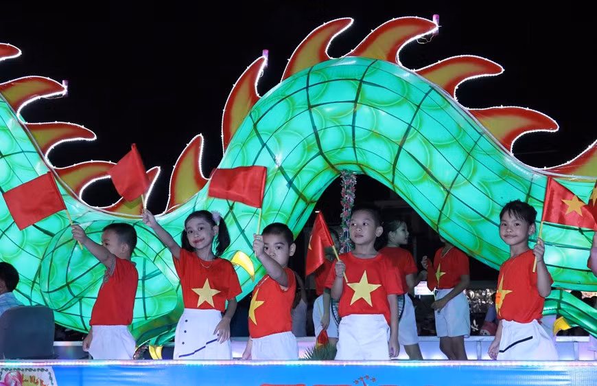 Los niños disfrutan de los modelos gigantes de linternas del Festival del Medio Otoño que desfilan por las calles de Tuyen Quang.