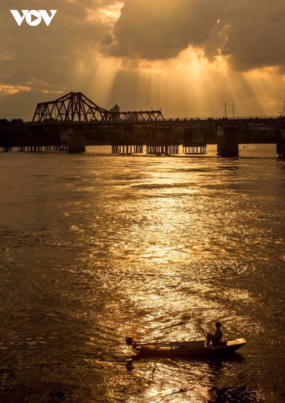 Los trabajadores se ganan la vida en el río bajo los rayos del sol al final del día.
