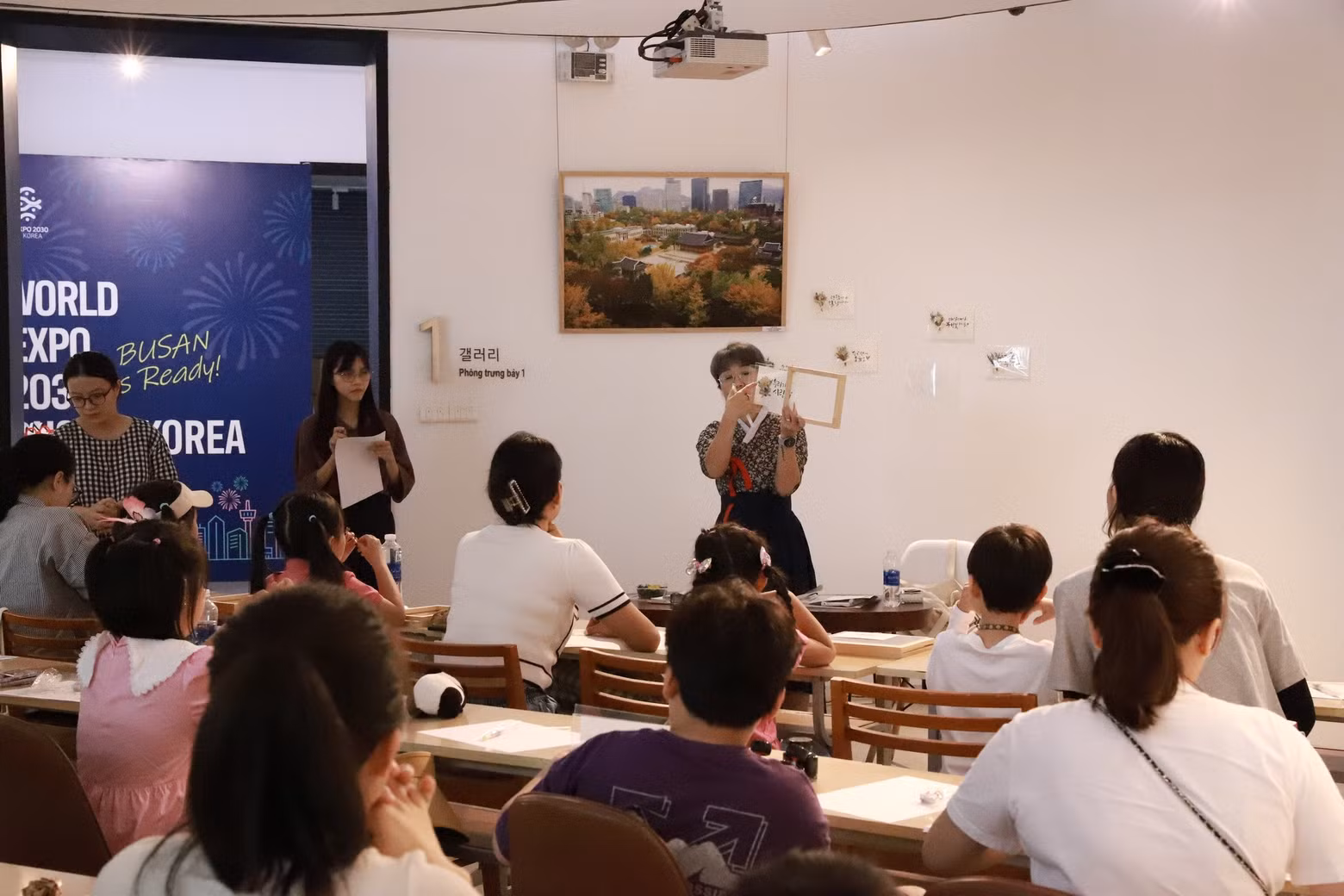 Bajo la instrucción de una maestra surcoreana, las familias participantes aprenden a escribir al estilo caligráfico palabras, frases o una extracción de la letra de su canción favorita.