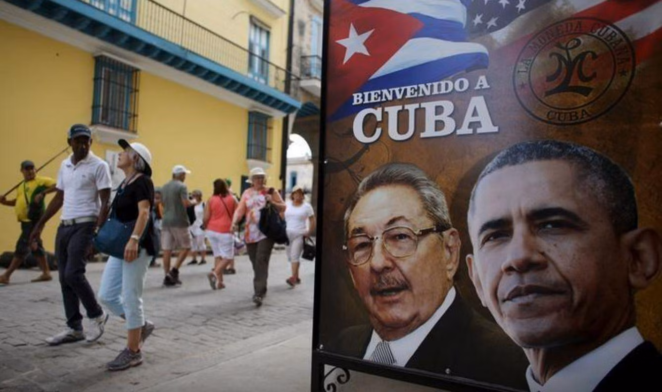 Unos turistas pasan junto un cartel con las efigies del presidente de Estados Unidos, Barack Obama, y de Cuba, Raúl Castro, colocado en la entrada a un restaurante en La Habana, el 17 de marzo de 2016. (Foto: Reuters)