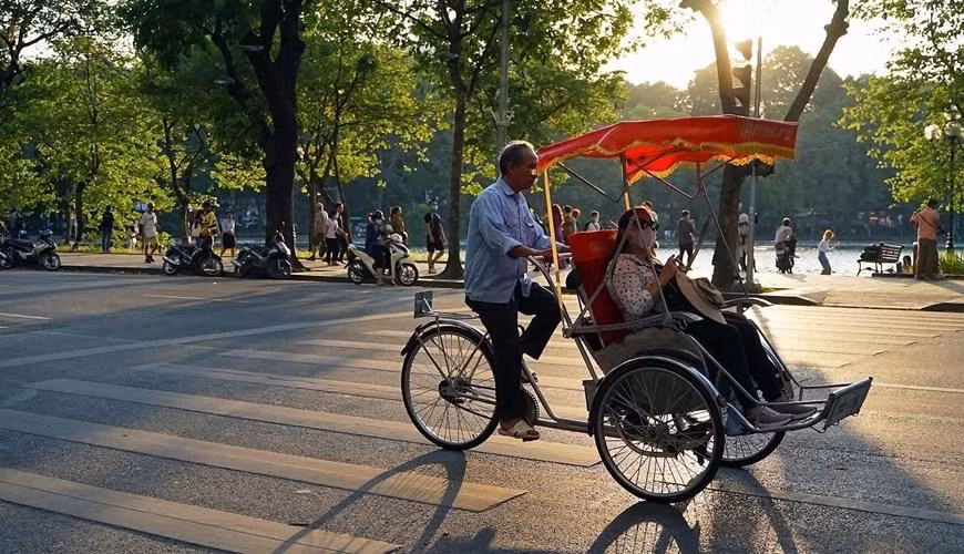 Turistas extranjeros experimentan triciclos alrededor del lago Hoan Kiem.