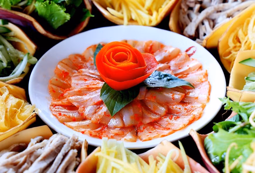 El plato de pescado Mai de color blanco está salpicado de pimientos rojos brillantes y colocados en el medio como "pistilo" El plato de pescado Mai de color blanco está salpicado de pimientos rojos brillantes y colocados en el medio como "pistilo"