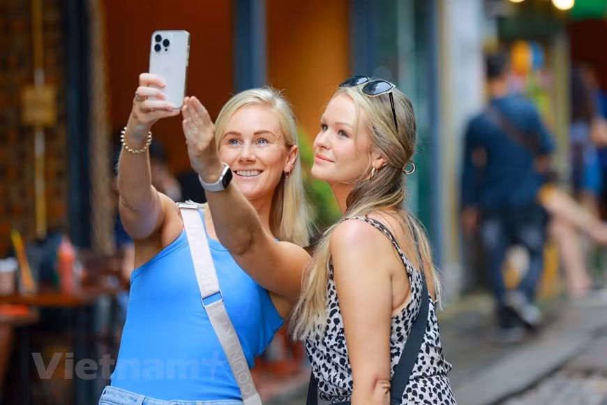 Mujeres turistas toman fotos libremente en las calles de Hanói sin temor a condiciones inseguras.