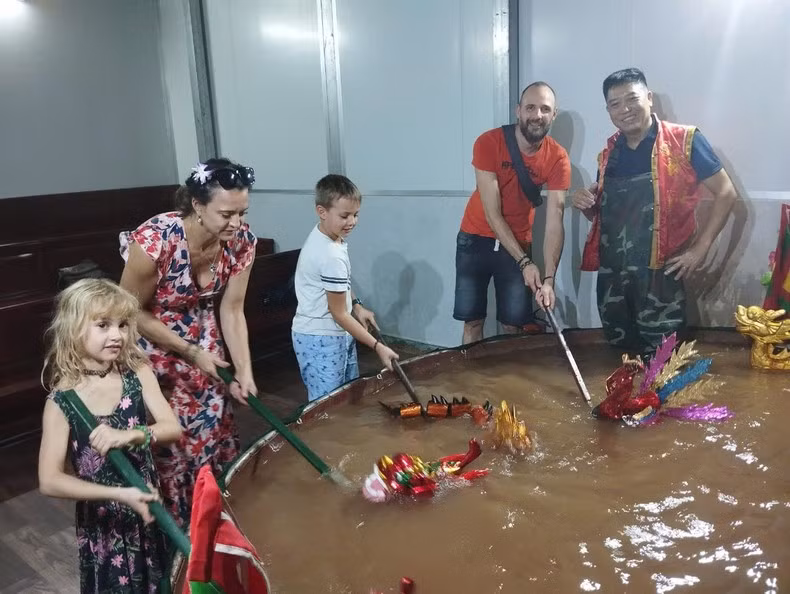 Los niños extranjeros están interesados en las marionetas acuáticas vietnamitas.