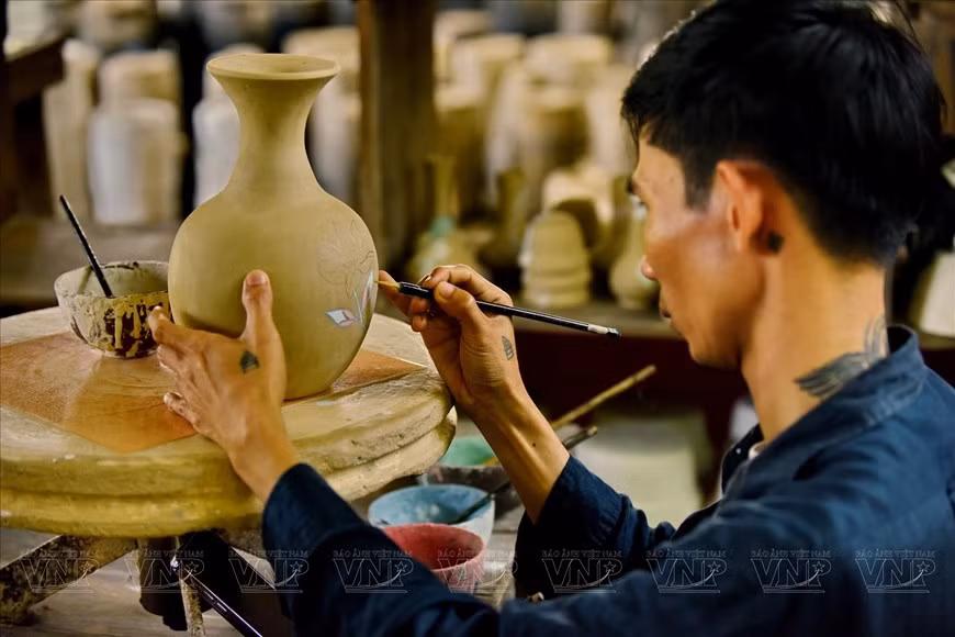 Un joven alfarero decora un jarrón de cerámica. (Foto: Revista Ilustrada de Vietnam)
