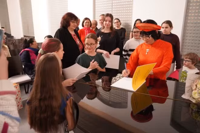 La artista Kieu Anh firma autógrafos para estudiantes y padres en un concierto celebrado en el Palacio Zichy de Bratislava, Eslovaquia, a finales de febrero de 2026. (Foto: VNA)