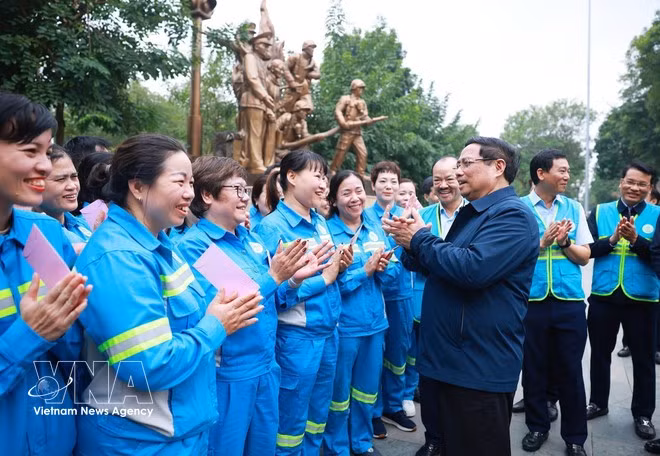 El primer ministro Pham Minh Chinh y trabajadores ambientales. (Foto: VNA)