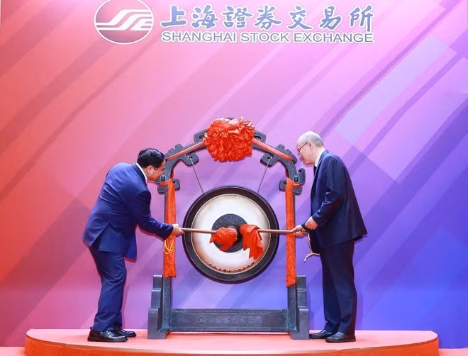 El primer ministro Pham Minh Chinh (izquierda) realiza la ceremonia de toque de gong para inaugurar la sesión bursátil en la Bolsa de Shanghái. (Foto: VNA)