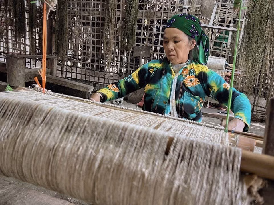 Una mujer Hmong en la aldea textil Lung Tam tejiendo telas a mano en telares de madera tradicionales.