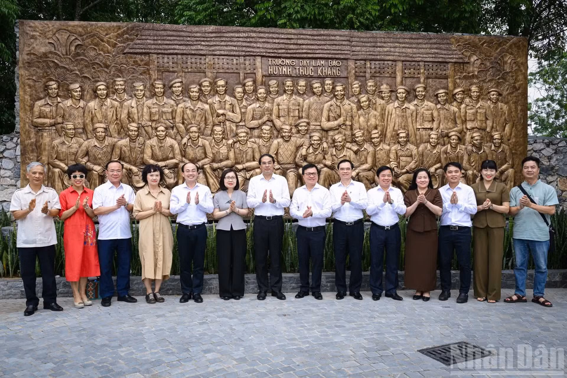 Delegados se toman una foto conmemorativa frente a un retrato en relieve de los 48 miembros de la Junta Directiva, profesores y estudiantes de la escuela de periodismo Huynh Thuc Khang.