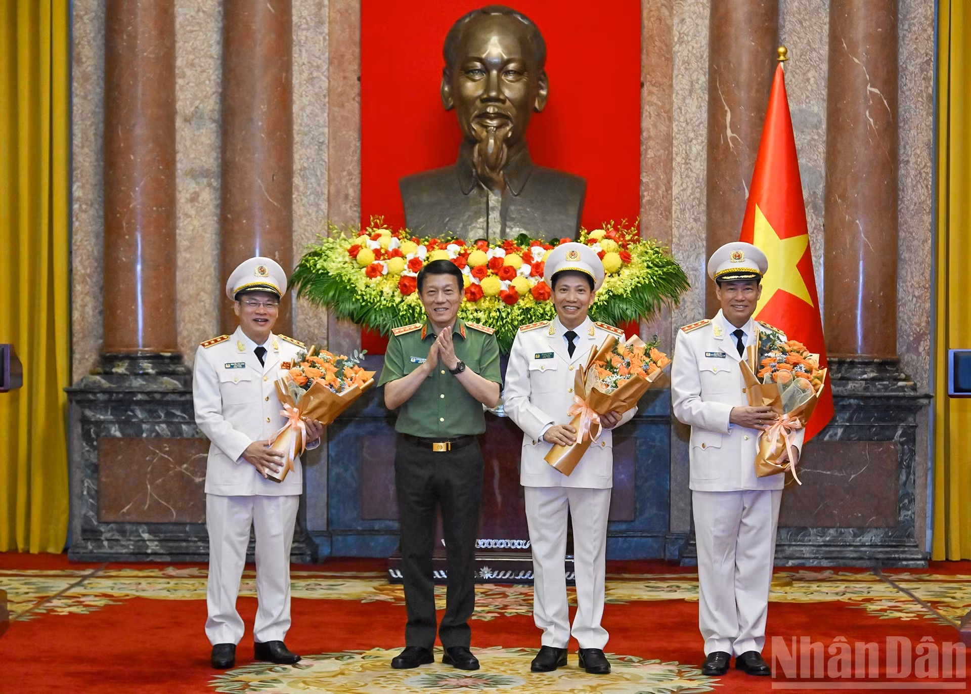 El ministro de Seguridad Pública, Luong Tam Quang, entrega flores para felicitar a Le Tan Toi, Le Van Tuyen y Nguyen Van Long.
