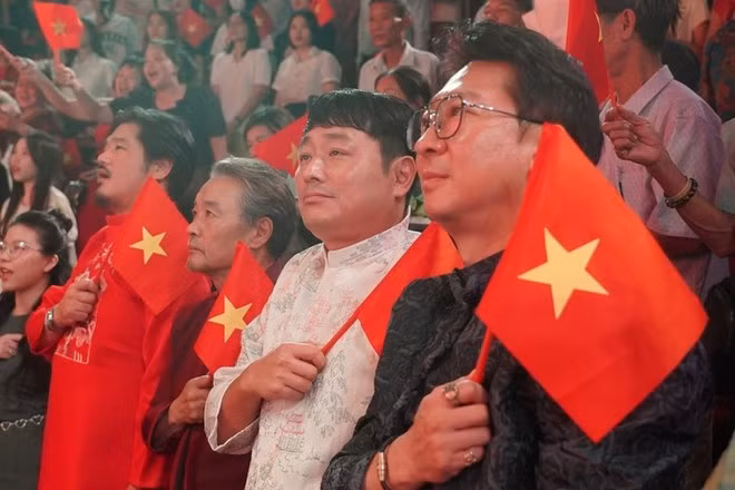 El equipo de producción surcoreano, con Ao Dai y la bandera nacional vietnamita, observa el programa. De derecha a izquierda: el director artístico Park Hyun Woo y el director Cho Joon Hui. (Foto: Teatro de Drama de Vietnam)