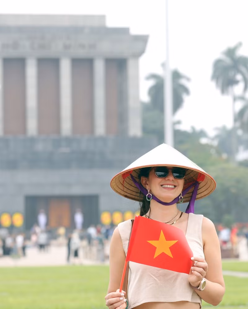 Los visitantes extranjeros disfrutan tomándose fotos con la bandera vietnamita.