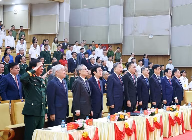 Los delegados saludan la bandera nacional en la ceremonia por el 110º aniversario del natalicio del secretario general Nguyen Van Linh.