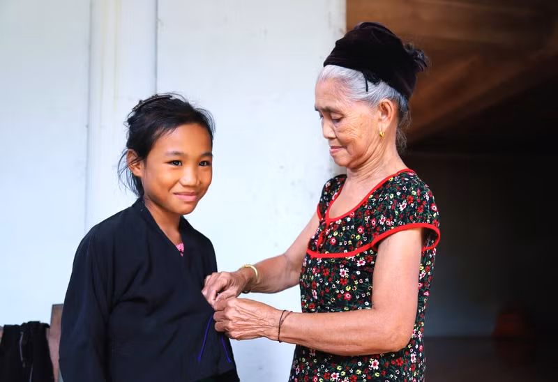 Los niños O'du aprenden de los adultos cómo vestir el traje tradicional antes de participar en la ceremonia del primer trueno, el ritual de atado de hilos en la muñeca y la ceremonia de nombramiento.