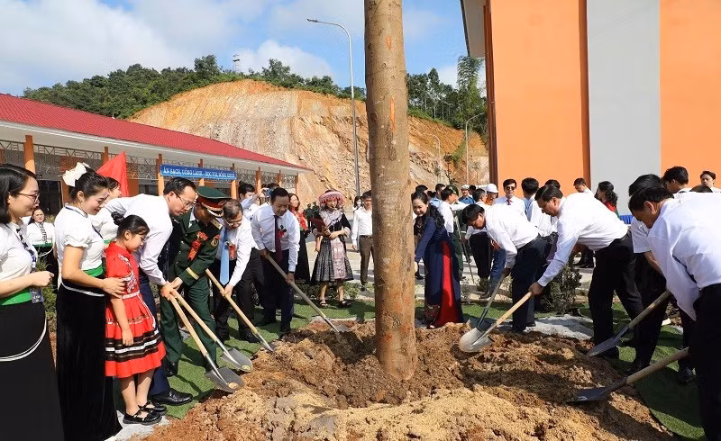 Gia Tuc y otros delegados plantan árboles en el recinto de la escuela.
