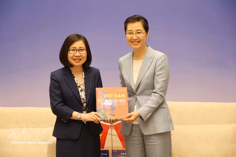 La subdirectora general de la VNA, Doan Thi Tuyet Nhung (izquierda), entrega a la vicepresidenta de Xinhua, Xi Yanchun, el libro fotográfico bilingüe vietnamita-inglés “Vietnam: 40 años de Renovación”, publicado por la VNA. (Foto: VNA)