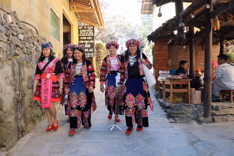 Turistas vestidos con trajes tradicionales del pueblo Lo Lo recorren Lung Cu en Tuyen Quang.
