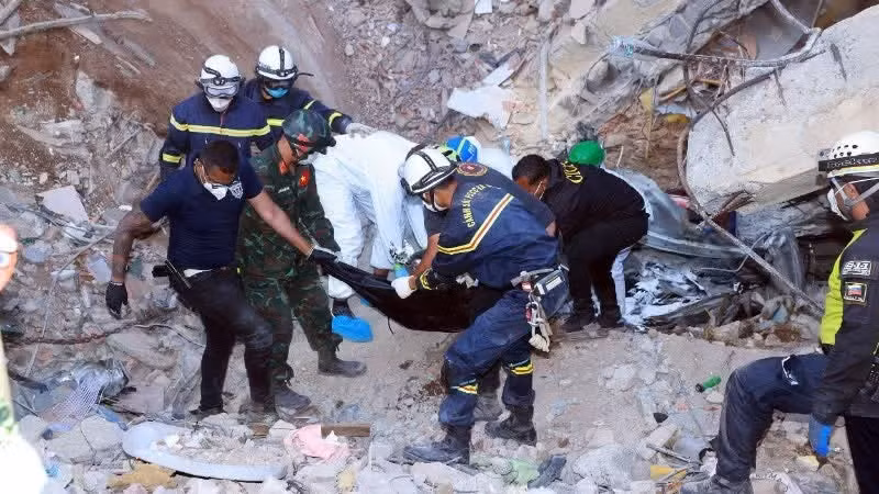 Los brigadistas vietnamitas entregan los cuerpos recuperados entre los escombros a las autoridades locales.