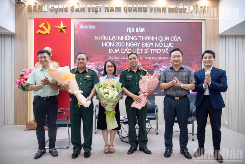 El editor adjunto del periódico Nhan Dan, Phan Van Hung, entrega flores a los invitados participantes en el coloquio.