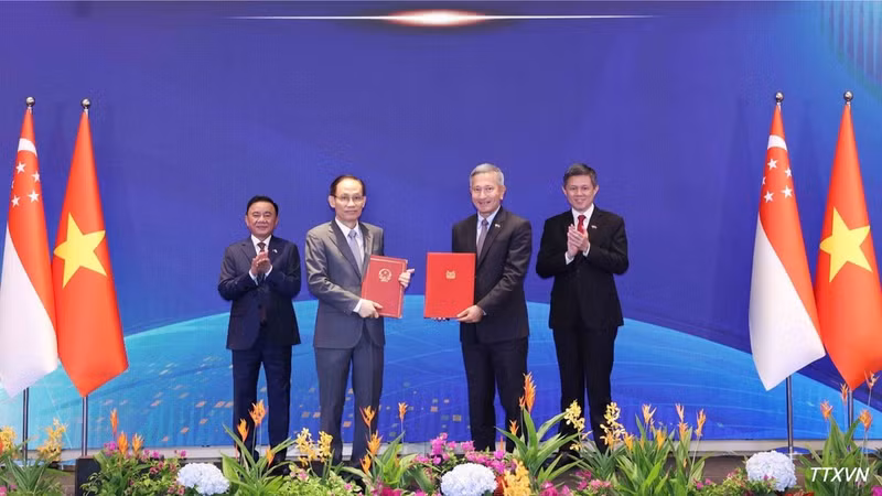 El miembro del Buró Político y ministro de Relaciones Exteriores de Vietnam, Le Hoai Trung, y el canciller de Singapur, Vivian Balakrishnan, intercambian firmas del Memorando de Entendimiento sobre cooperación entre los dos Partidos. (Foto: VNA)